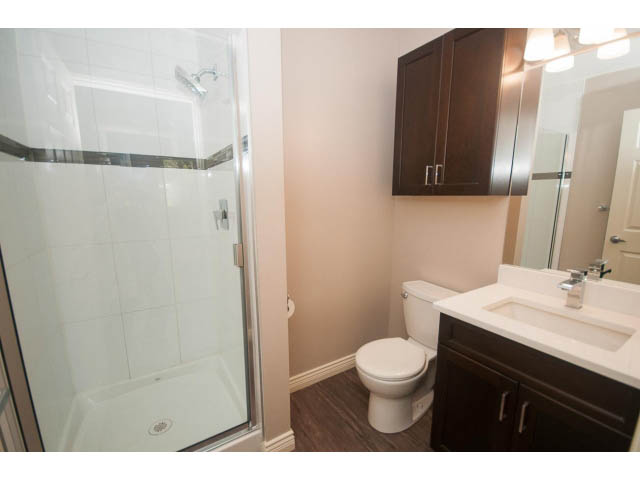 Bright bathroom with dark wood cabinets, white countertop, and shower. - 4135 Golf drive, North Vancouver