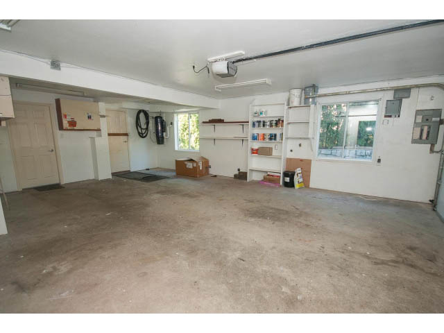 Spacious unfinished basement with concrete floor, exposed pipes, and shelving units. - 4135 Golf drive, North Vancouver