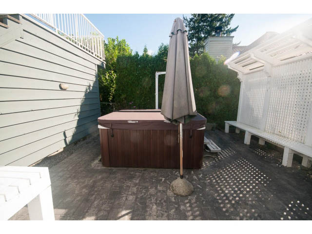 Furnished patio with wooden deck, outdoor umbrella, and greenery backdrop. - 4135 Golf drive, North Vancouver