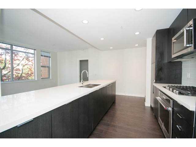 Bright kitchen with white countertops, hardwood floors, and a city view. - 414 - 255 West 1st St, North Vancouver