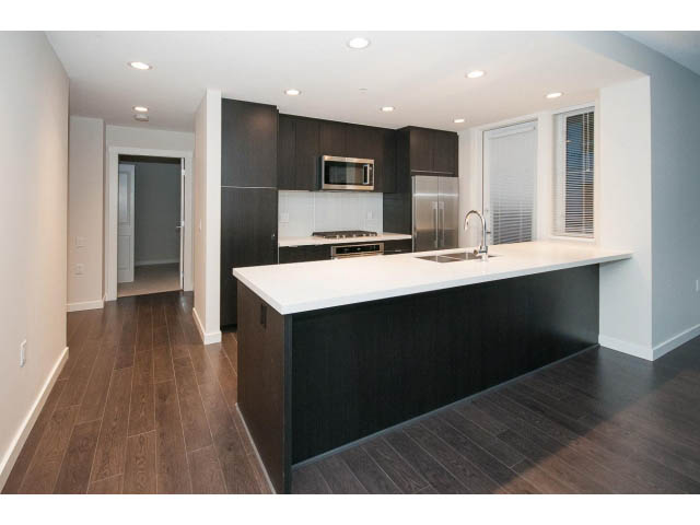 Bright kitchen with white countertops, dark wood cabinets, and hardwood floors. - 414 - 255 West 1st St, North Vancouver