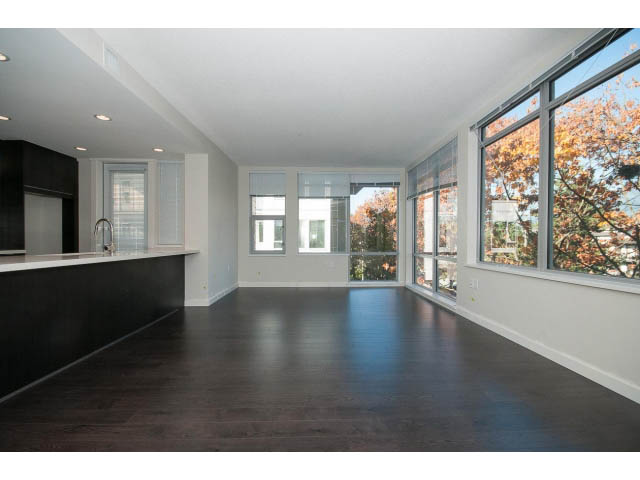 Bright living room with hardwood floors and large windows showcasing a city view. - 414 - 255 West 1st St, North Vancouver