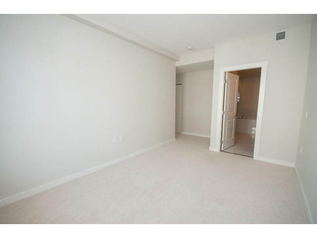 Bright living room with carpeted floors and a door leading to another room. - 414 - 255 West 1st St, North Vancouver