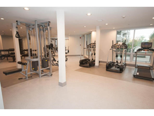 Spacious gym with cardio machines and weight equipment, large windows offering city views. - 414 - 255 West 1st St, North Vancouver