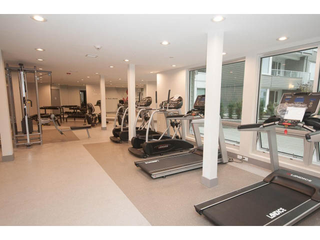 Spacious gym with treadmills and mirrors, large windows offering city views. - 414 - 255 West 1st St, North Vancouver