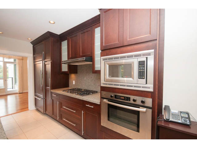Bright kitchen with dark wood cabinets, granite countertops, and stainless steel appliances. - 708 - 4685 Valley Dr, Vancouver West Side