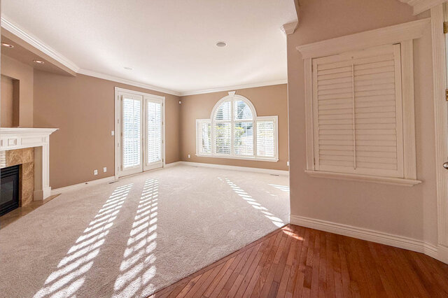 Formal living room with carpet, a fireplace with a white mantel and marble surround, French doors and a tall arched window wi