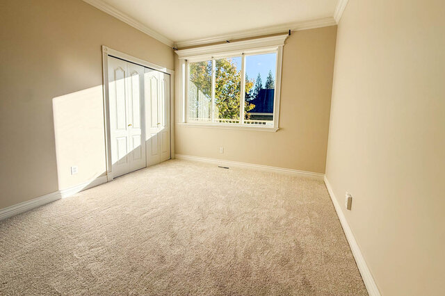 Carpeted bedroom with a double closet, crown moulding and a window onto trees. - 3858 Sauve Place, North Vancouver