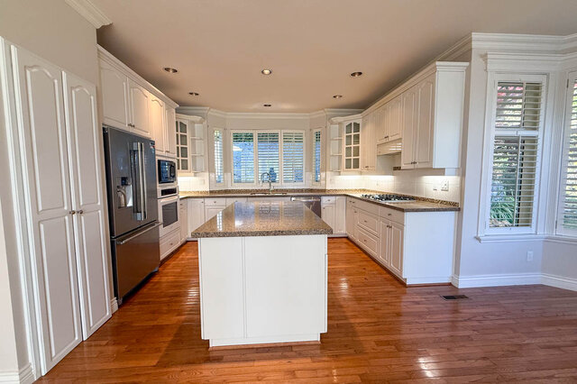 Kitchen with a granite island, stainless French-door fridge, built-in microwave and wall oven, gas cooktop, tall pantry cabin