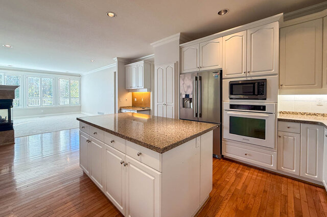 Kitchen island and appliance wall open to the family room with its fireplace and wall of windows. - 3858 Sauve Place, North Vancouver