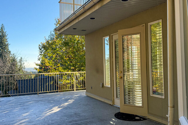 Lower-level patio with a railing and a door into the lower level, the upper balcony above. - 3858 Sauve Place, North Vancouver