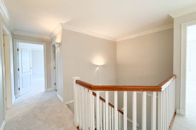 Upstairs hall with carpet and an open railing over the stairs, doors to the bedrooms. - 3858 Sauve Place, North Vancouver