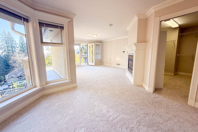 Large primary bedroom with a fireplace, a big bay window over the trees and neighbourhood, a walk-in closet and doors to the 