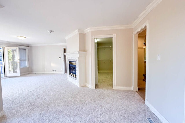 Primary bedroom fireplace between the balcony doors and the walk-in closet, the ensuite through the doorway. - 3858 Sauve Place, North Vancouver