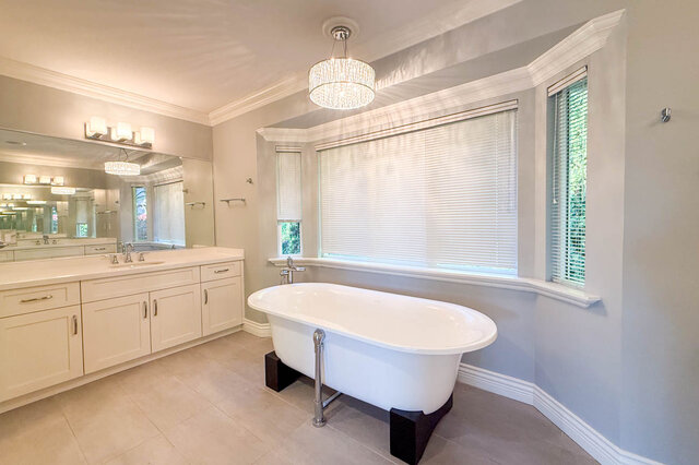 Ensuite with the freestanding clawfoot tub under a crystal chandelier and a double-sink vanity on the left. - 3858 Sauve Place, North Vancouver