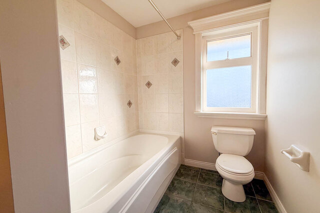 Upstairs bathroom tub with a tile surround beside a frosted window. - 3858 Sauve Place, North Vancouver