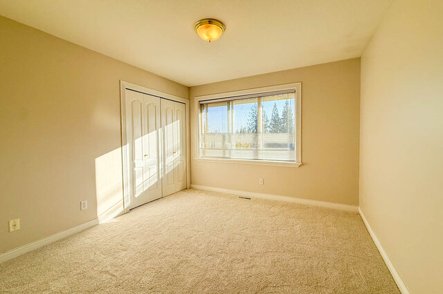Sunny bedroom with carpet, a double closet and a window onto evergreens. - 3858 Sauve Place, North Vancouver