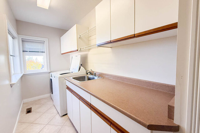 Laundry room with a washer and dryer, a sink, a long counter and wall cabinets. - 3858 Sauve Place, North Vancouver