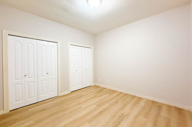 Lower-level bedroom with hardwood floors and two double closets. - 3858 Sauve Place, North Vancouver