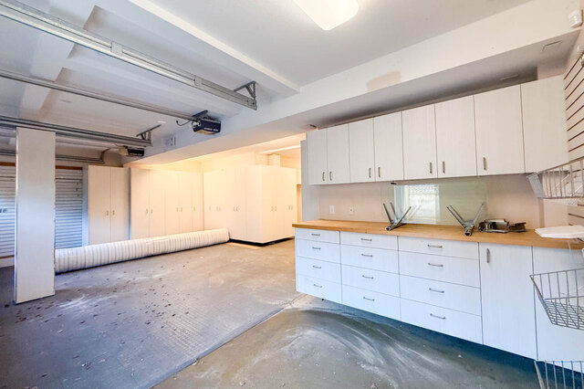 Attached double garage lined with built-in cabinets and a long workbench. - 3858 Sauve Place, North Vancouver