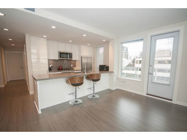 Bright kitchen with modern appliances and hardwood floors, featuring a city view. - 524 - 255 West 1st St, North Vancouver