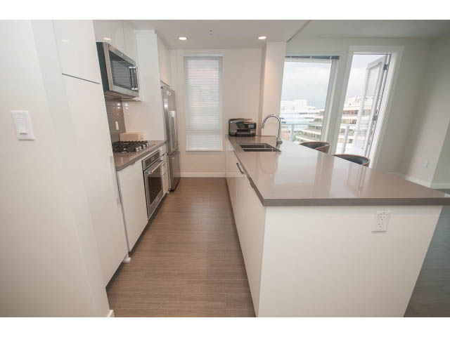 Bright kitchen with white countertops, hardwood floors, and a city view. - 524 - 255 West 1st St, North Vancouver