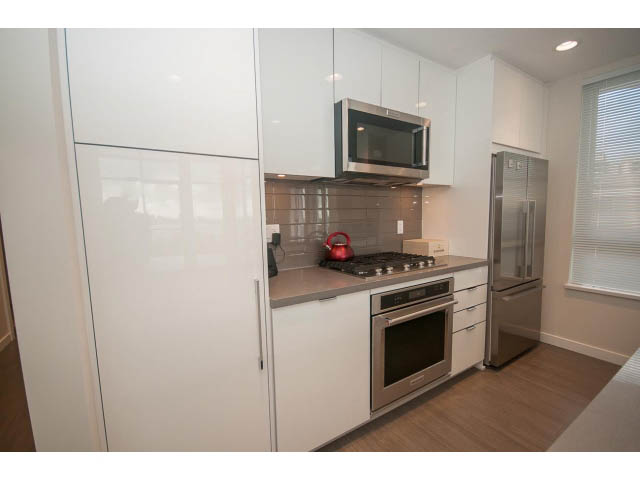 Bright kitchen with white cabinets, stainless steel appliances, and hardwood floors. - 524 - 255 West 1st St, North Vancouver