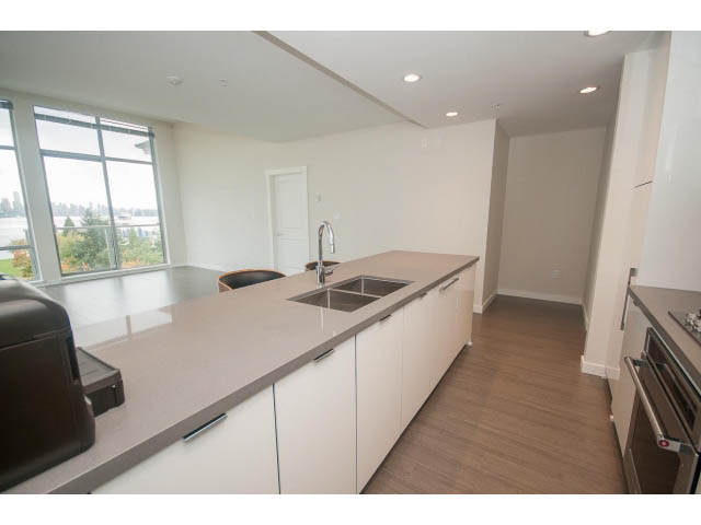 Bright kitchen with modern white cabinetry, hardwood floors, and a city view. - 524 - 255 West 1st St, North Vancouver
