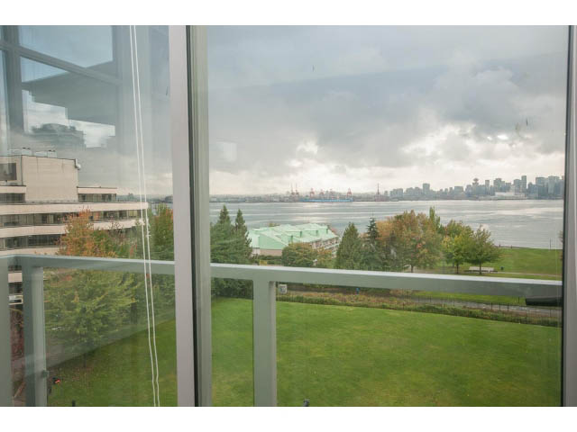 Bright living room with panoramic city view and lush greenery outside. - 524 - 255 West 1st St, North Vancouver