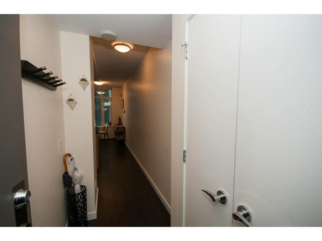 Bright hallway with white walls and wooden flooring, leading to a door with a silver handle. - 802 - 1708 Columbia St, Vancouver West Side