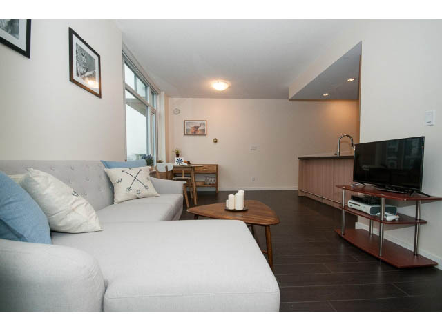 Bright living room with modern furniture, hardwood floors, and a view of the kitchen. - 802 - 1708 Columbia St, Vancouver West Side