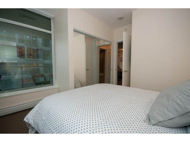 Bright bedroom with a neatly made bed and a large window offering a city view. - 802 - 1708 Columbia St, Vancouver West Side