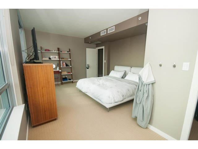 Bright living room with white furniture, large window, and wooden entertainment unit. - 2401 - 1005 Beach Avenue, Vancouver Downtown