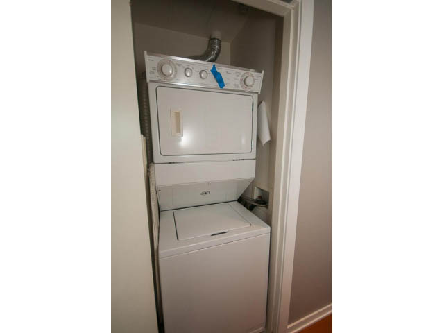 Bright laundry room with stacked washer and dryer, clean white surfaces. - 2401 - 1005 Beach Avenue, Vancouver Downtown