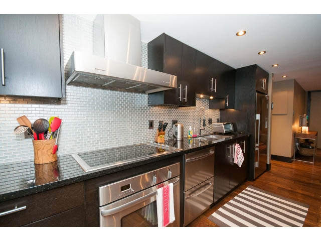Bright kitchen with dark cabinets, stainless steel appliances, and hardwood floors. - 303 - 717 Jervis St, Vancouver Downtown