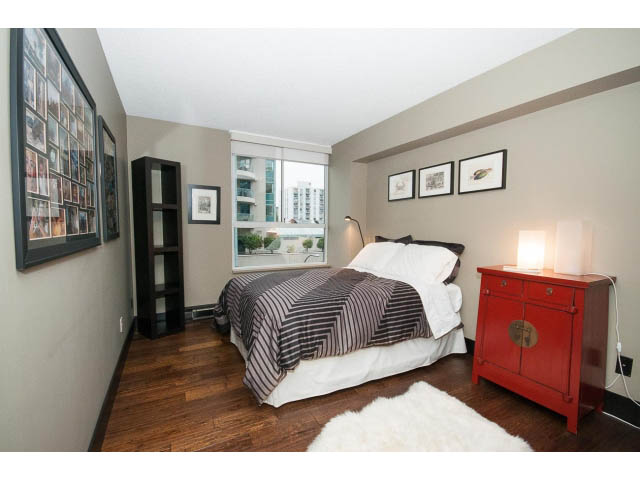 Bright bedroom with hardwood floors, city view, and red furniture. - 303 - 717 Jervis St, Vancouver Downtown
