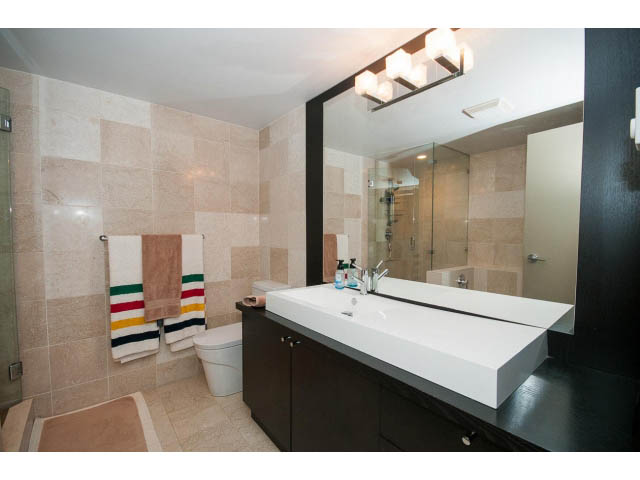 Modern bathroom with white countertops and beige tiled walls. - 303 - 717 Jervis St, Vancouver Downtown