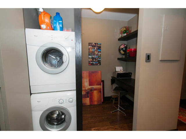 Bright laundry room with stacked washer and dryer, hardwood floors, and shelves. - 303 - 717 Jervis St, Vancouver Downtown