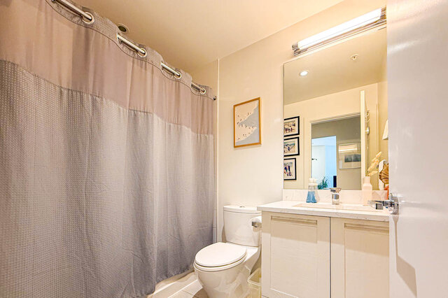 Bathroom with white vanity, marble countertop, and large mirror under a light fixture. - 503-105 West 2nd Street, North Vancouver