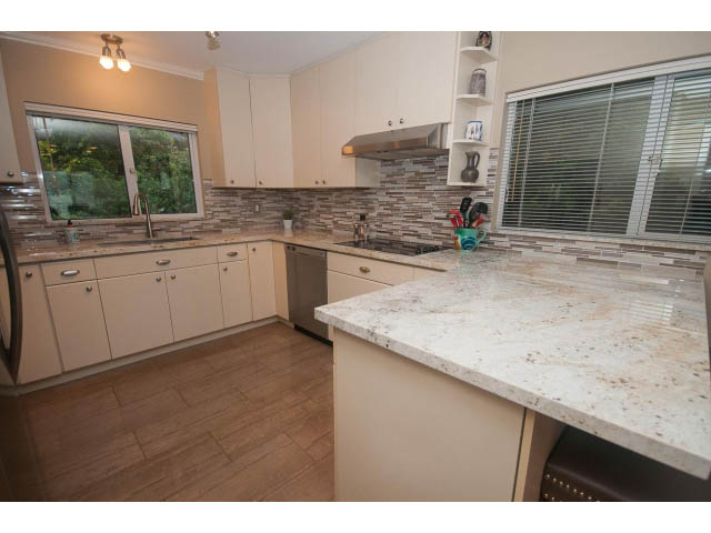 Bright kitchen with granite countertops, white cabinets, and a city view. - 8135 Pasco Rd, West Vancouver
