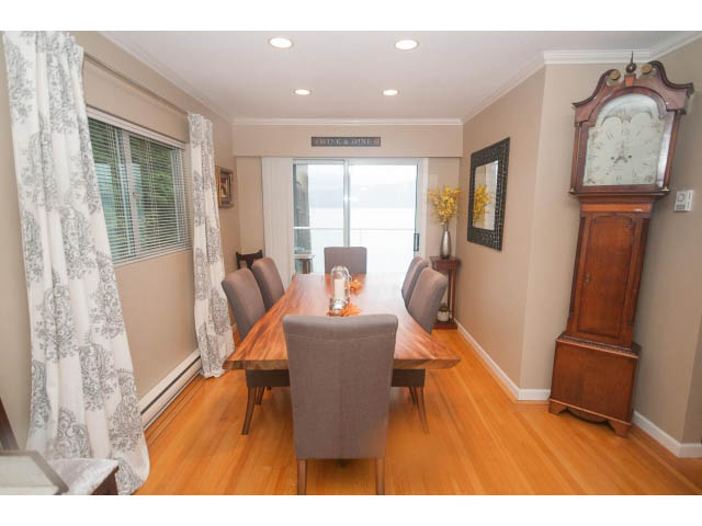 Furnished dining room with hardwood floors, large windows, and a grandfather clock. - 8135 Pasco Rd, West Vancouver