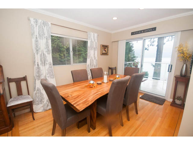 Furnished dining area with hardwood floors, large windows, and a view of the ocean. - 8135 Pasco Rd, West Vancouver