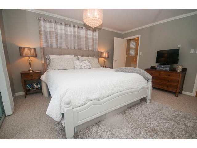 Spacious bedroom with plush rug, elegant chandelier, and cozy bedding. - 8135 Pasco Rd, West Vancouver