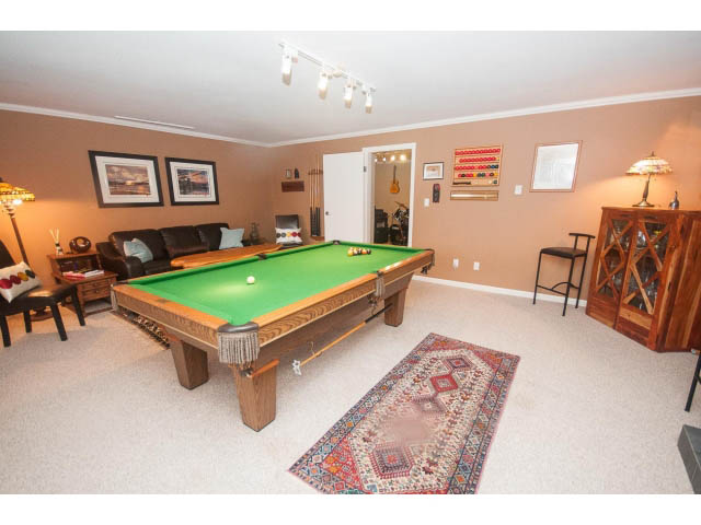Spacious living room with pool table, patterned rug, and cozy seating area. - 8135 Pasco Rd, West Vancouver
