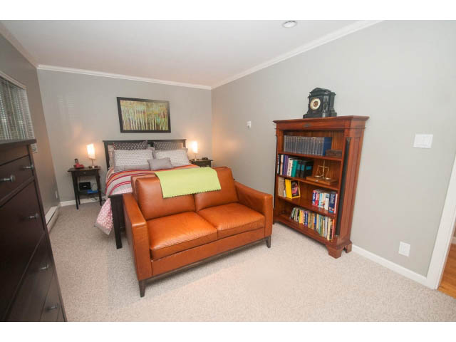 Spacious living room with leather couch, bookshelf, and cozy corner. - 8135 Pasco Rd, West Vancouver