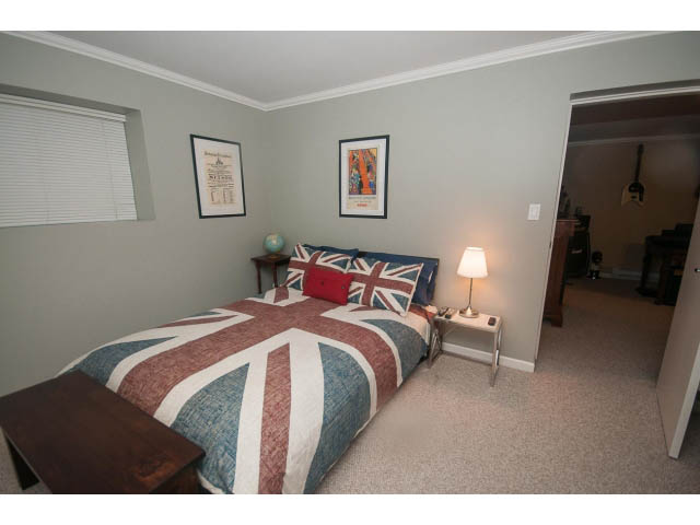 Bright bedroom with Union Jack-themed bedding and framed artwork on the walls. - 8135 Pasco Rd, West Vancouver