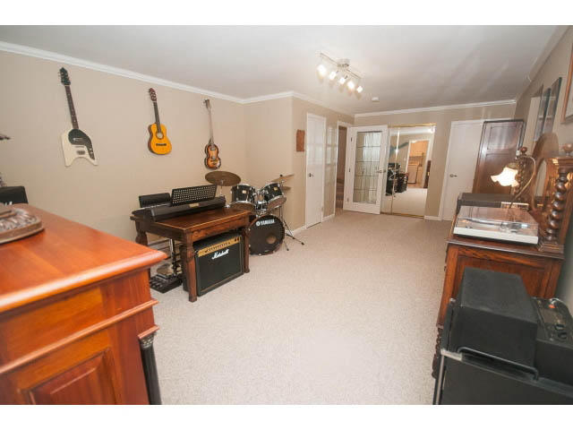 Spacious bedroom with wooden furniture, guitars, and a drum set. - 8135 Pasco Rd, West Vancouver