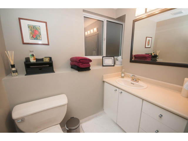 Bright bathroom with white countertops and a large mirror. - 8135 Pasco Rd, West Vancouver