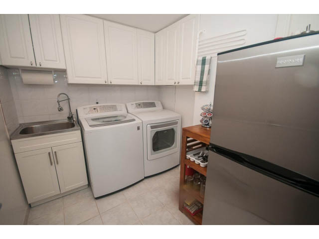 Bright kitchen with white cabinets, stainless steel appliances, and a countertop. - 8135 Pasco Rd, West Vancouver