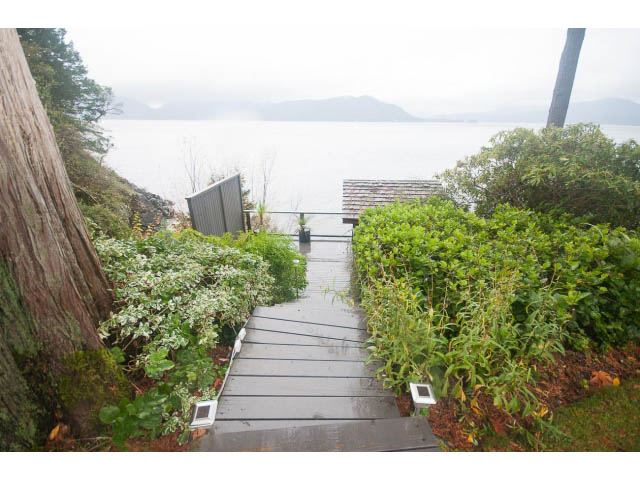 Furnished deck overlooking serene water and lush greenery. - 8135 Pasco Rd, West Vancouver